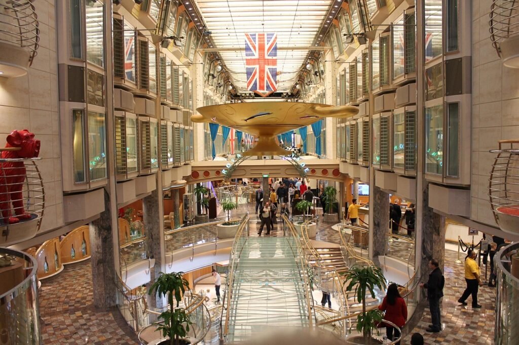 Cruise ship interior promenade with shops, cafes, and passengers walking