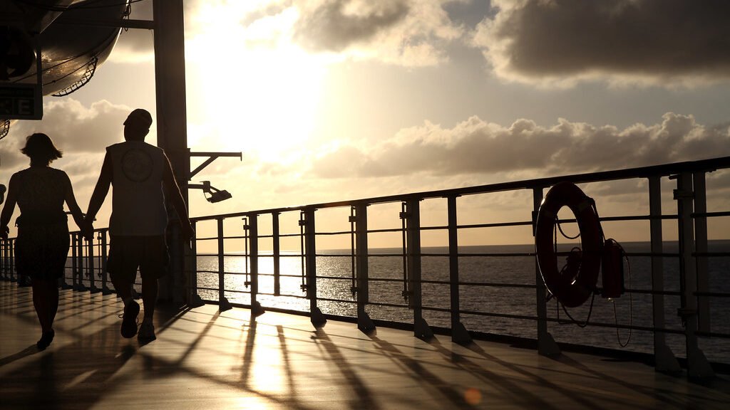 Joyful couple holding hands celebrating on cruise ship deck at sunset